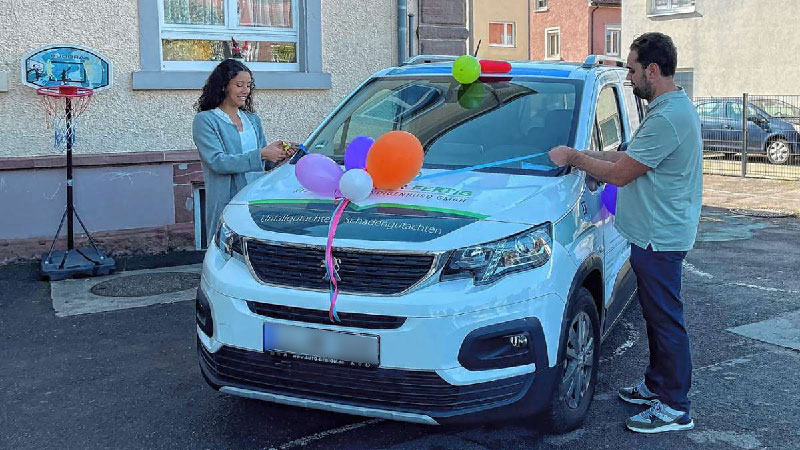 Julia Rabe schneidet symbolisch das um das Auto gewickelte Einweihungsband durch